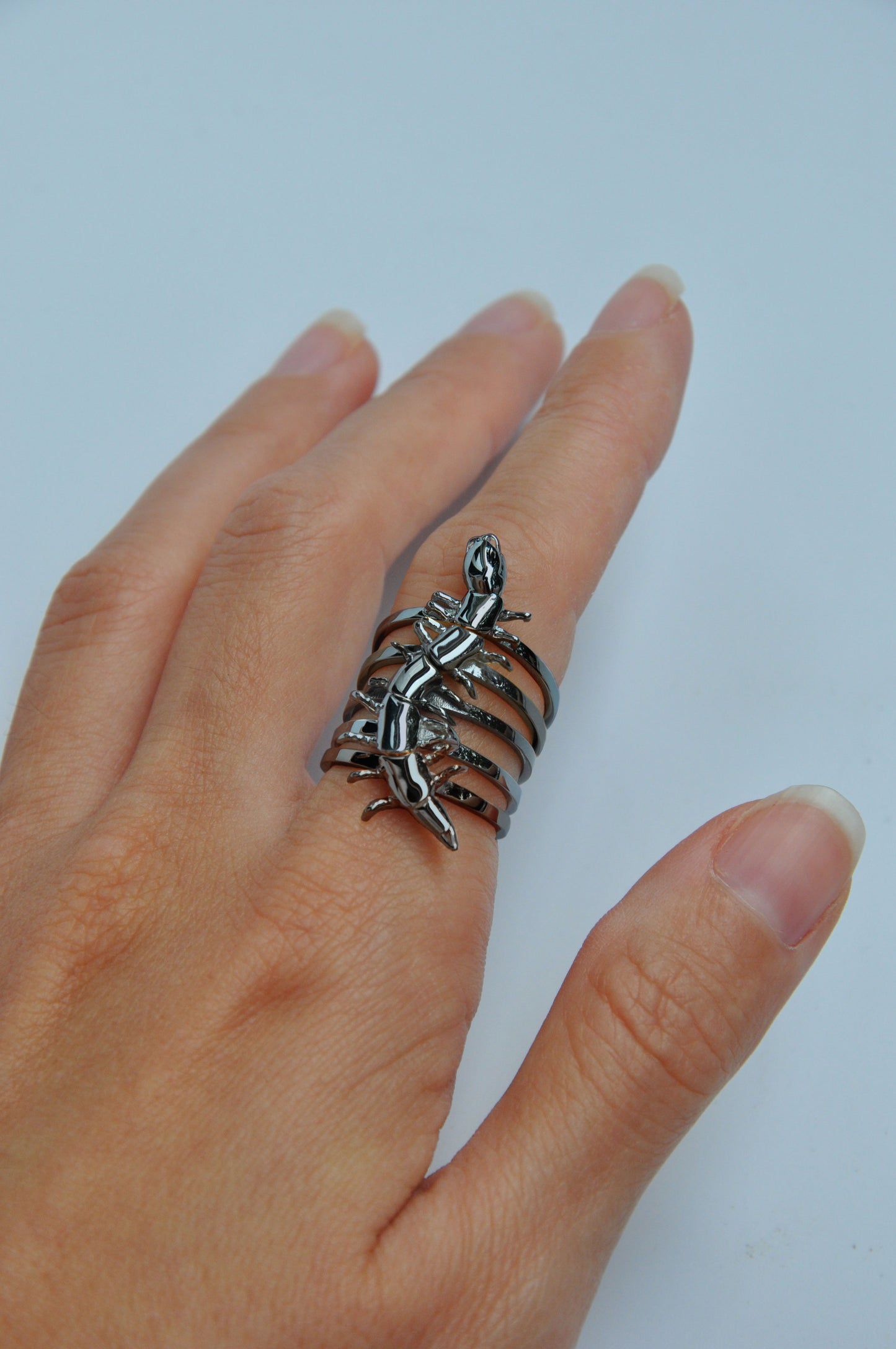 Full set of black rhodium-plated centipede stacking rings worn on a hand, featuring a cool-toned, high-shine surface.