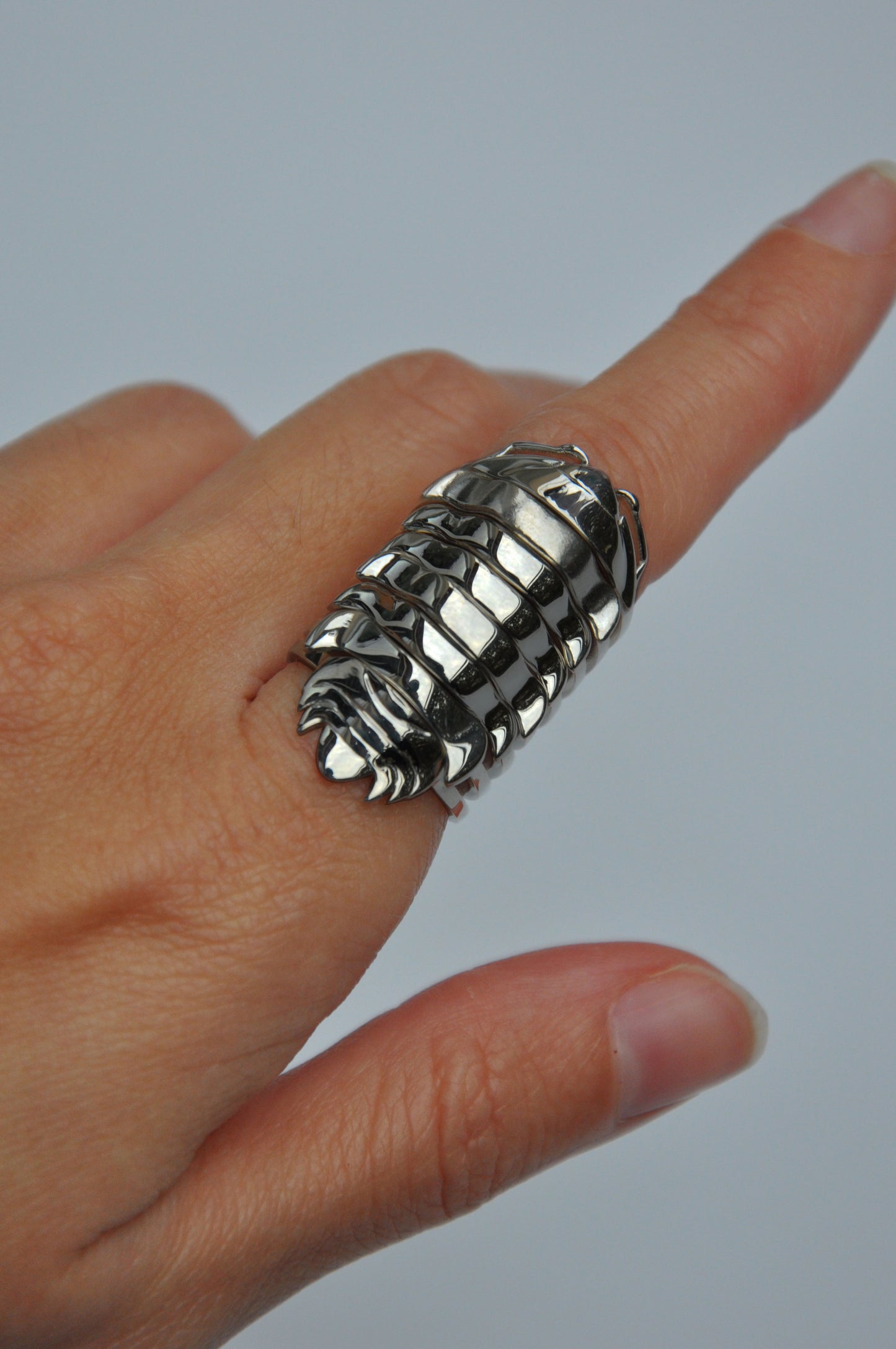 Sculptural black rhodium isopod rings stacked on finger, evoking layered armor and insect elegance.