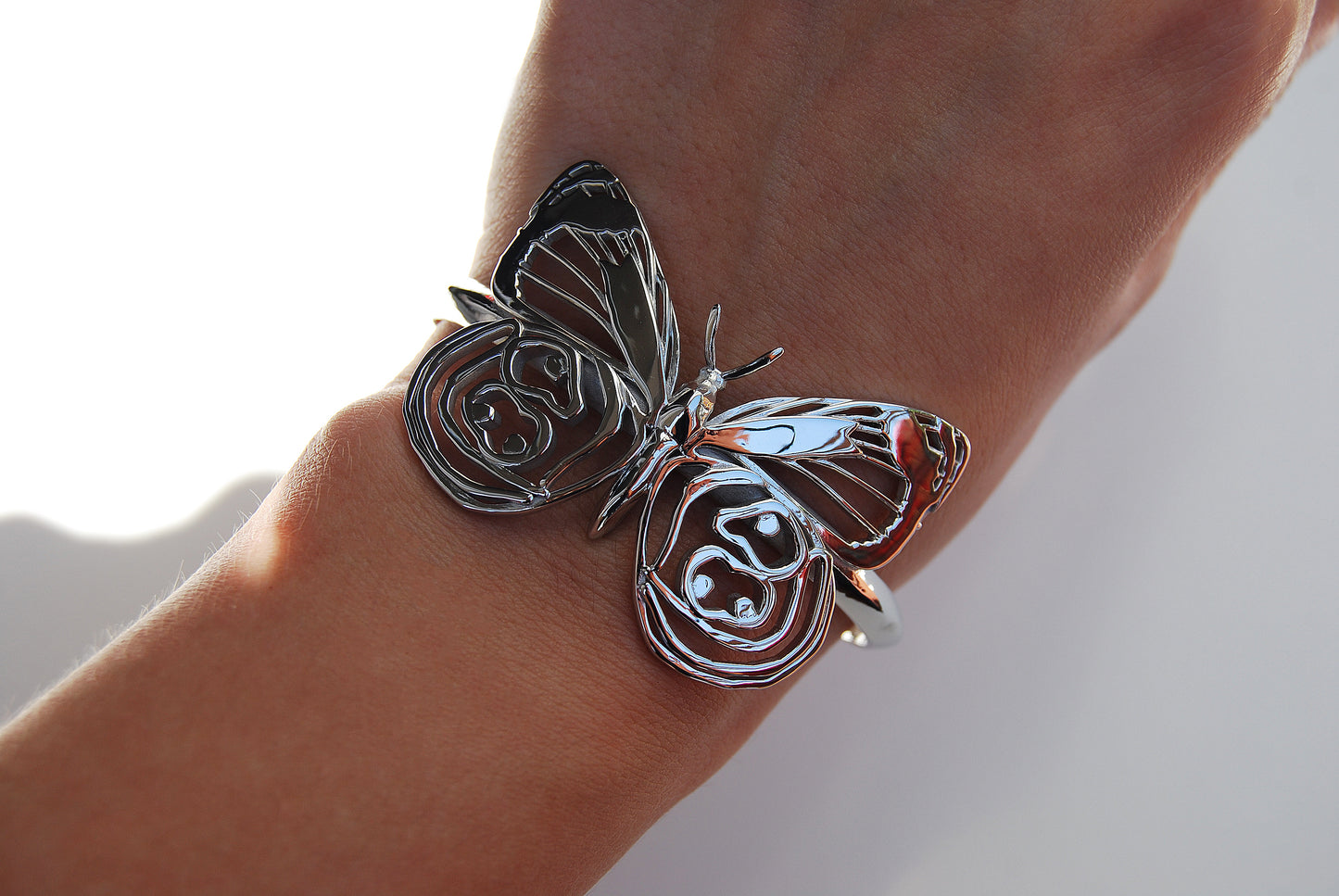 Silver Eighty-eight Butterfly Bracelet worn on hand against white background, highlighting size and fit.