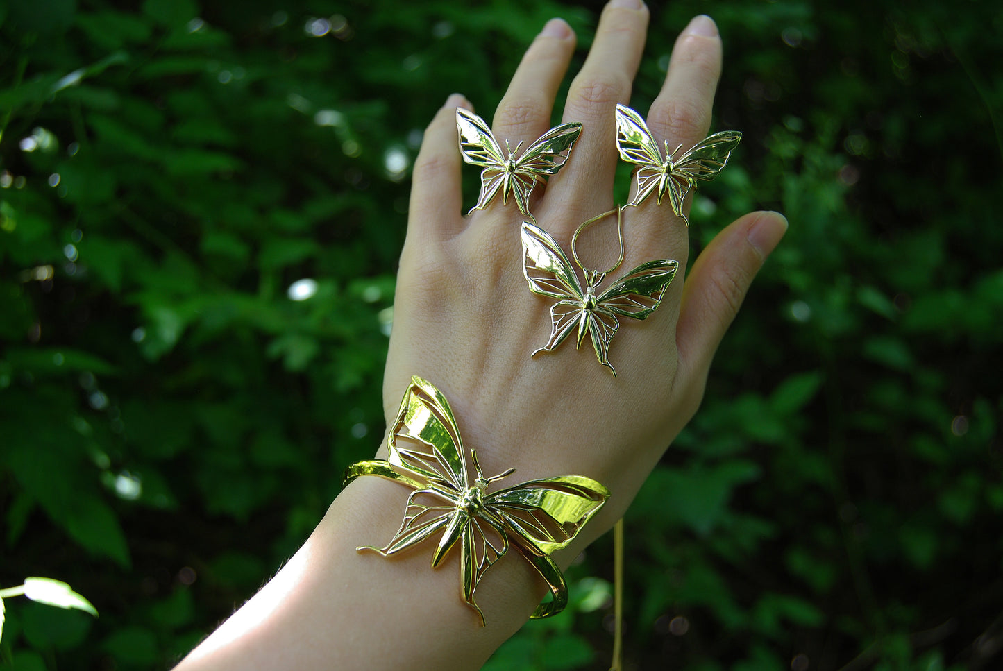 Collection of gold and silver butterfly pendant necklaces displayed on hand