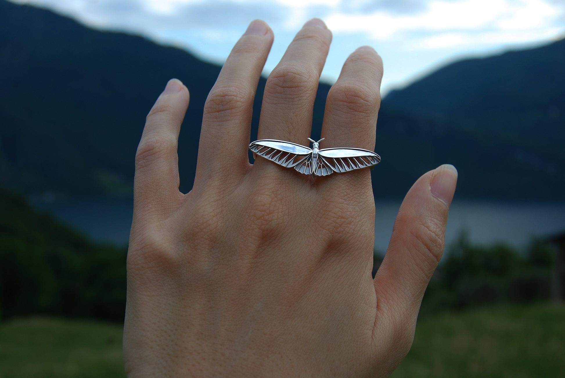 Sterling silver butterfly ring worn on hand, featuring thin silhouette and delicate wing cut-outs.