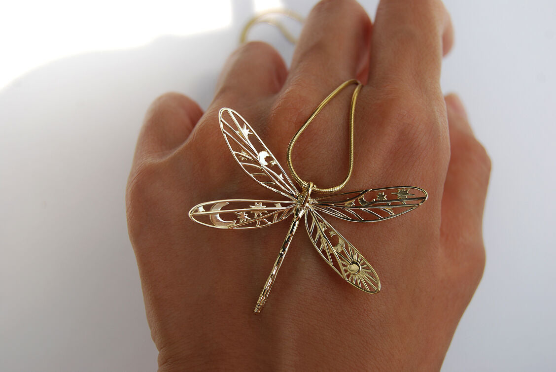 Gold damselfly pendant necklace displayed on hand