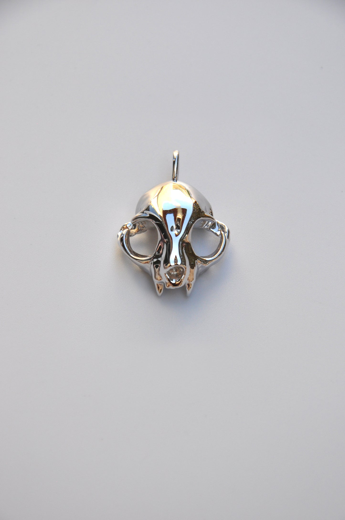 Bottom view of the matching silver feline skull earrings on a white background, highlighting detailed sculpting.