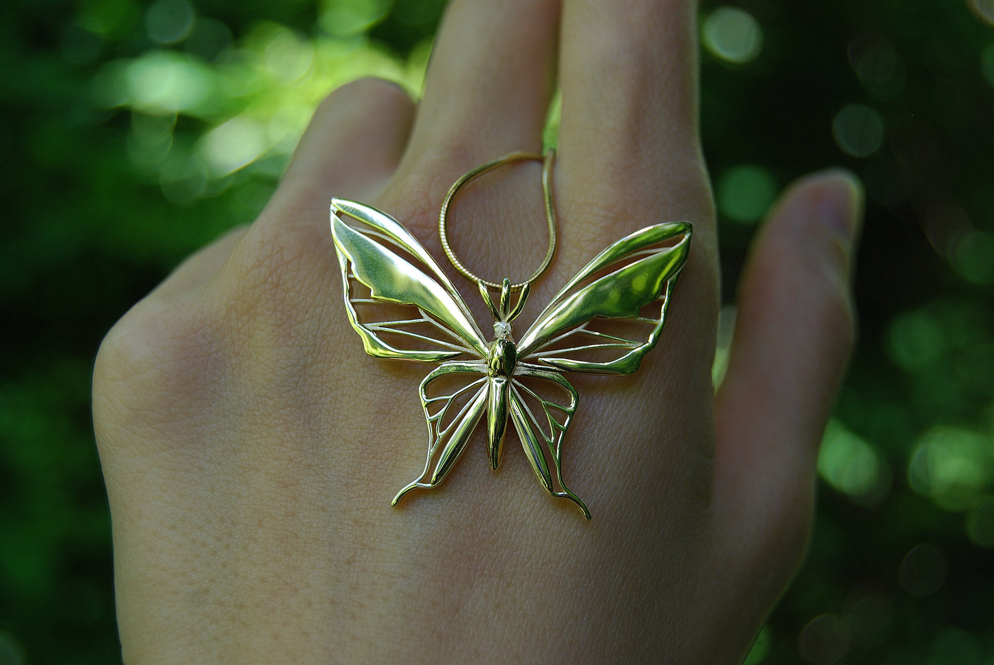 Close-up of gold butterfly pendant necklace on natural background