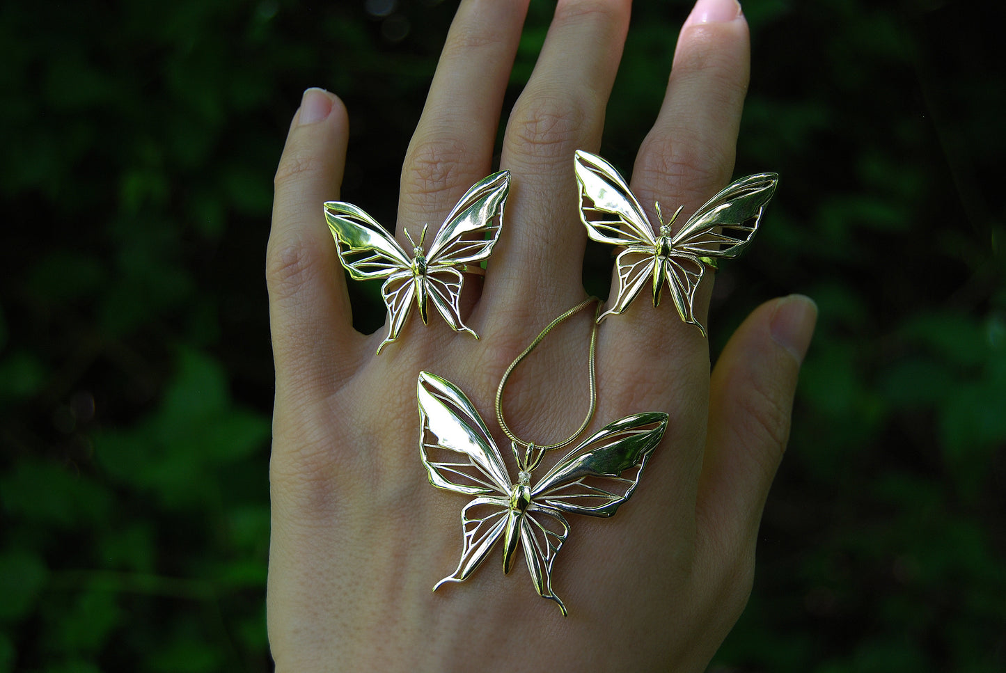 Collection of gold butterfly pendant necklaces displayed elegantly on hand