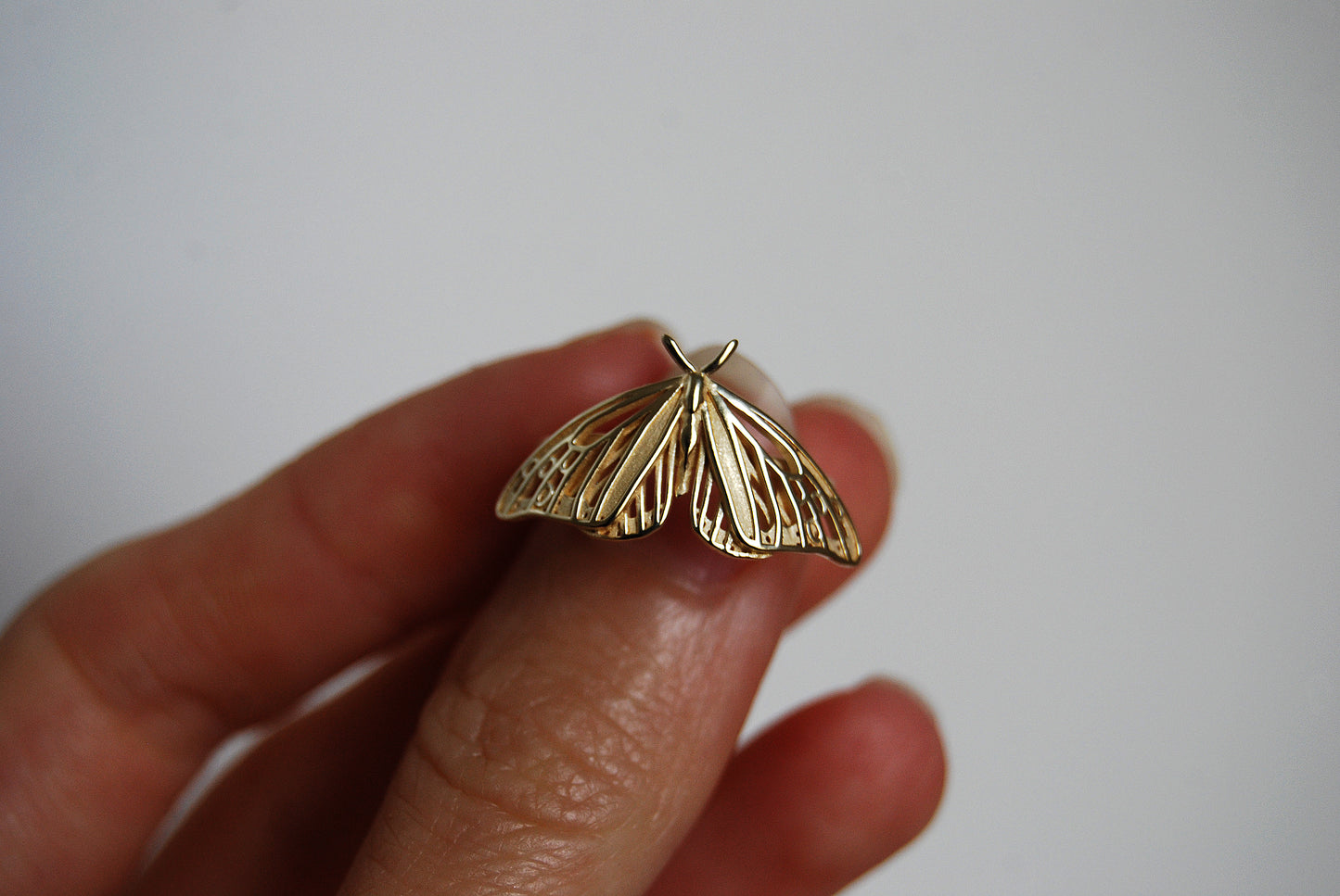 Close-up of hand holding Monarch Butterfly ring showing fine details and cutout design