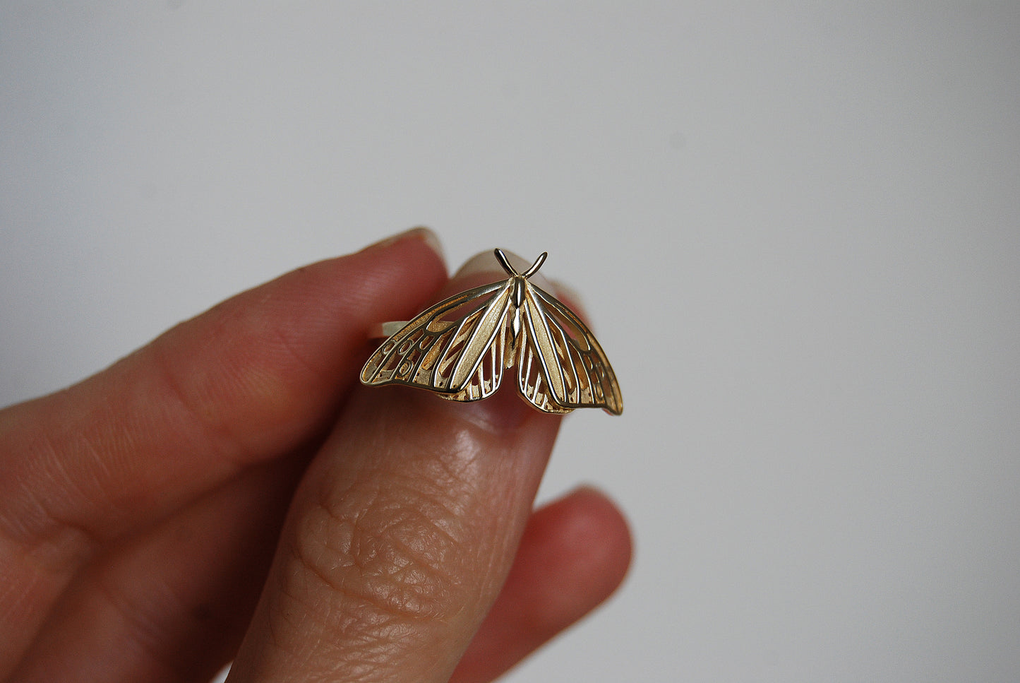 Hand holding a Monarch Butterfly ring with intricate Art Nouveau inspired design