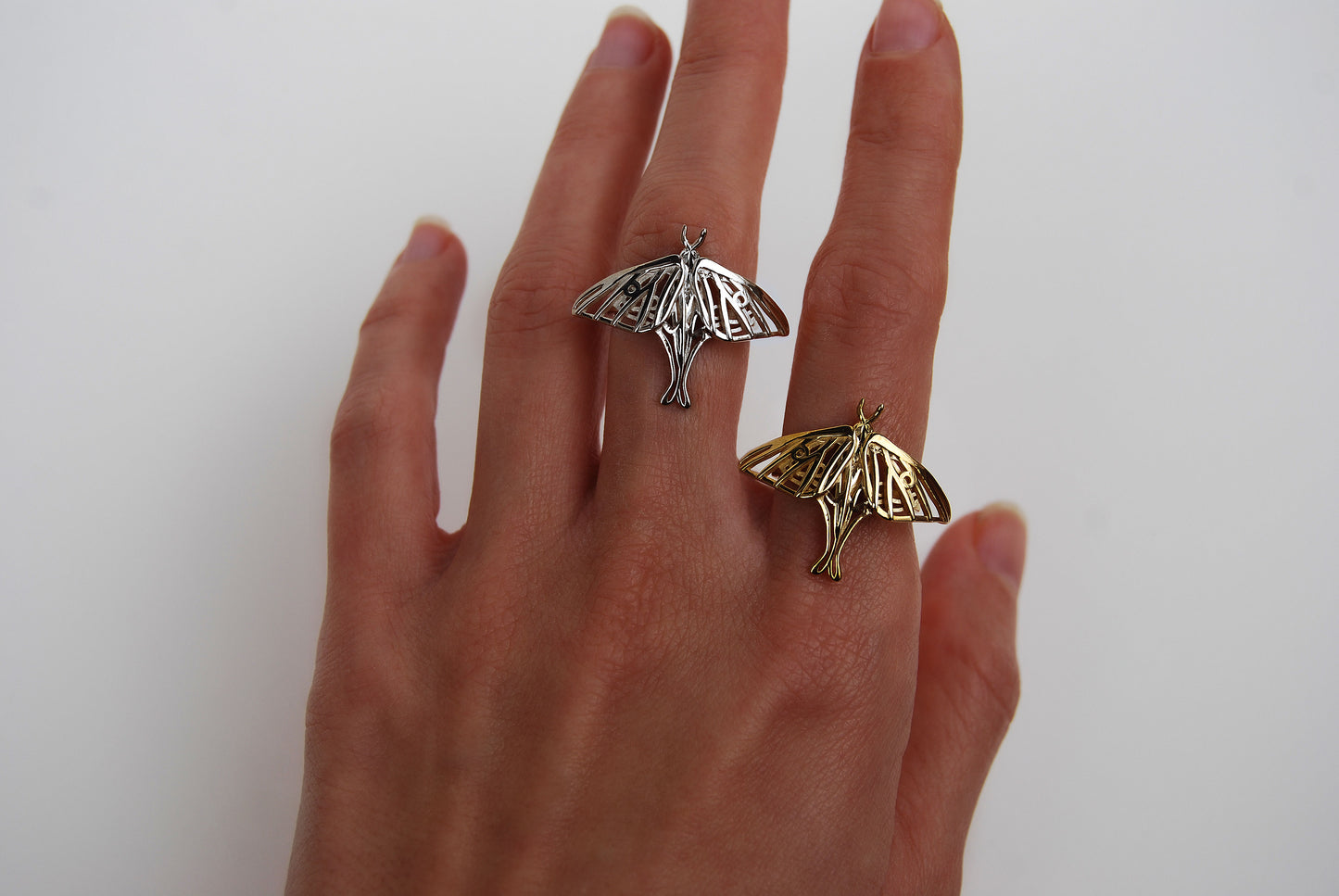 Both silver and gold Luna Moth Rings worn together on hand, showcasing color contrast and artistic variation.