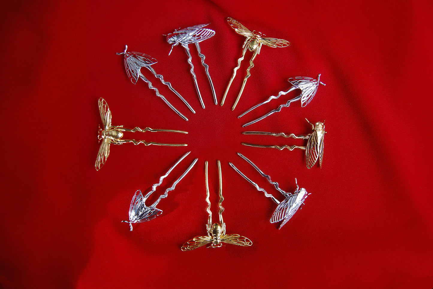Mandala arrangement of insect-inspired hair pins including Bee, Cicada, and Tiger Moth designs in silver, 14k gold, and bronze finishes, displayed in a circular pattern to highlight handcrafted detail and metallic textures.