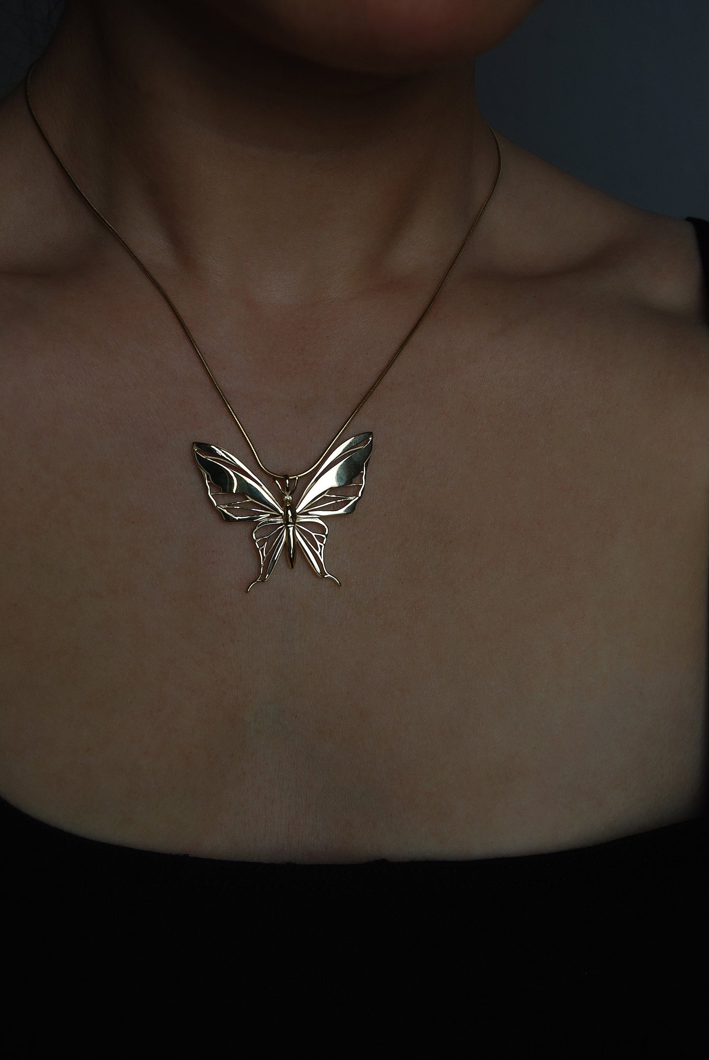 Model wearing gold butterfly pendant necklace
