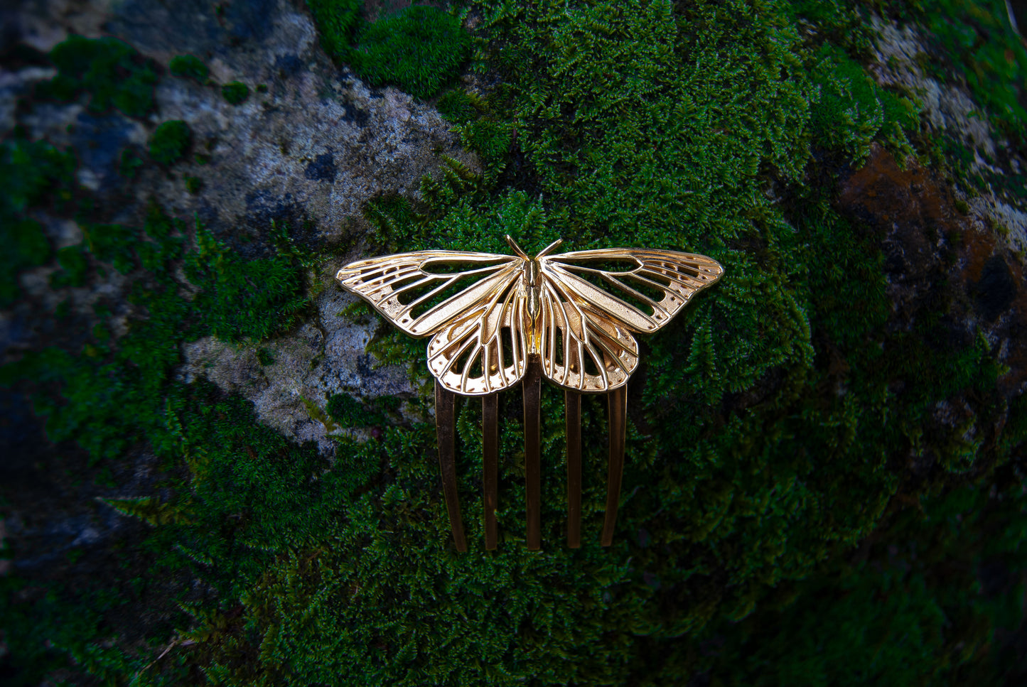 Monarch Butterfly hair comb in 14k gold-plated brass resting among natural foliage, showcasing its intricate cut-out design and elegant insect-inspired craftsmanship.