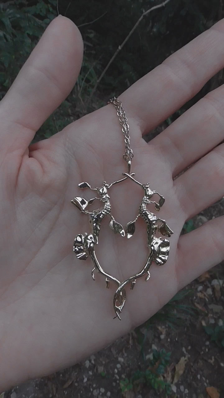 Video still of gold Weedy Sea Dragon Pendant being held, showcasing movement and polished surface.