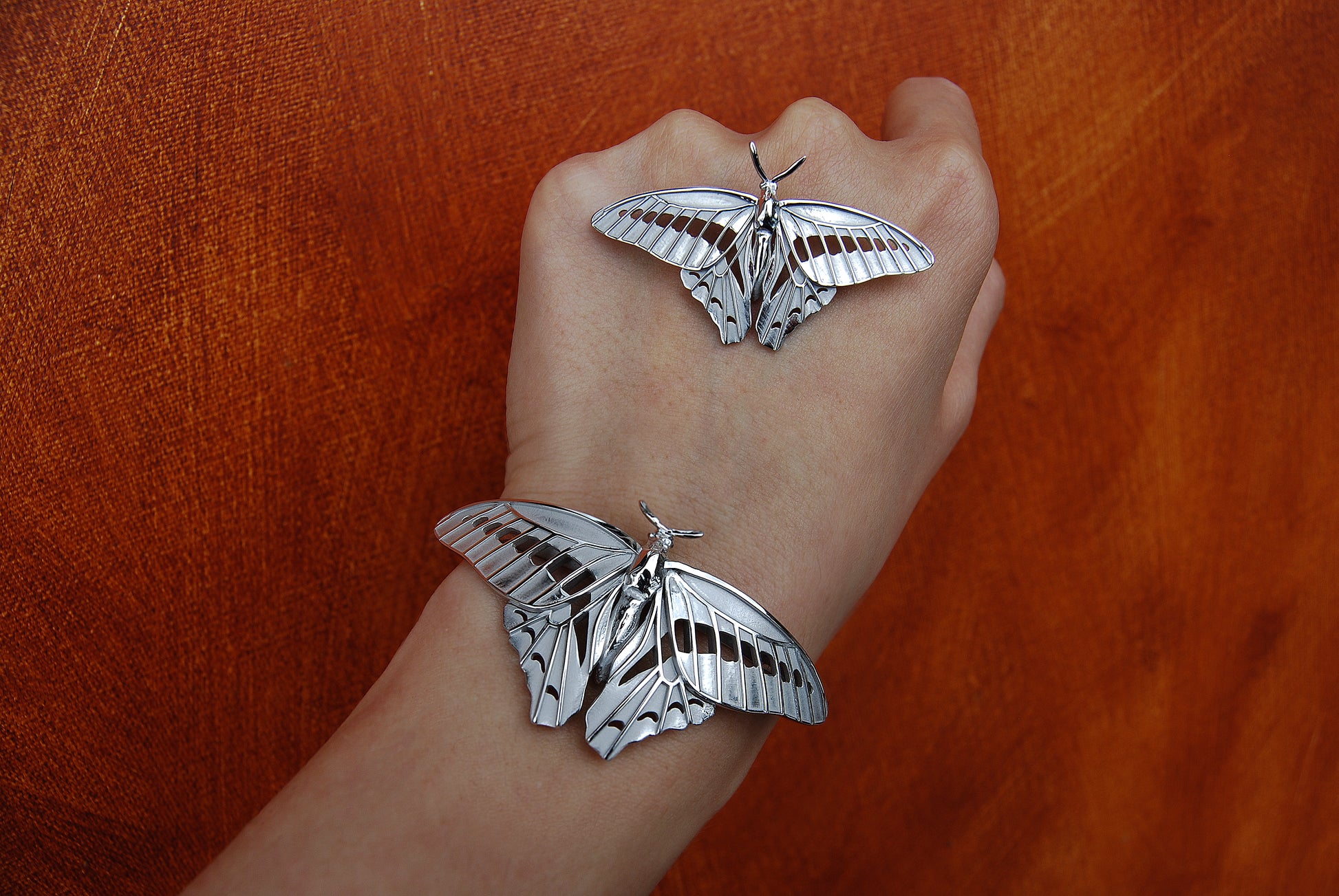 Sterling silver Blue Triangle Butterfly pendant and bracelet displayed in a natural outdoor setting with textured background, highlighting eco-friendly insect jewelry craftsmanship.