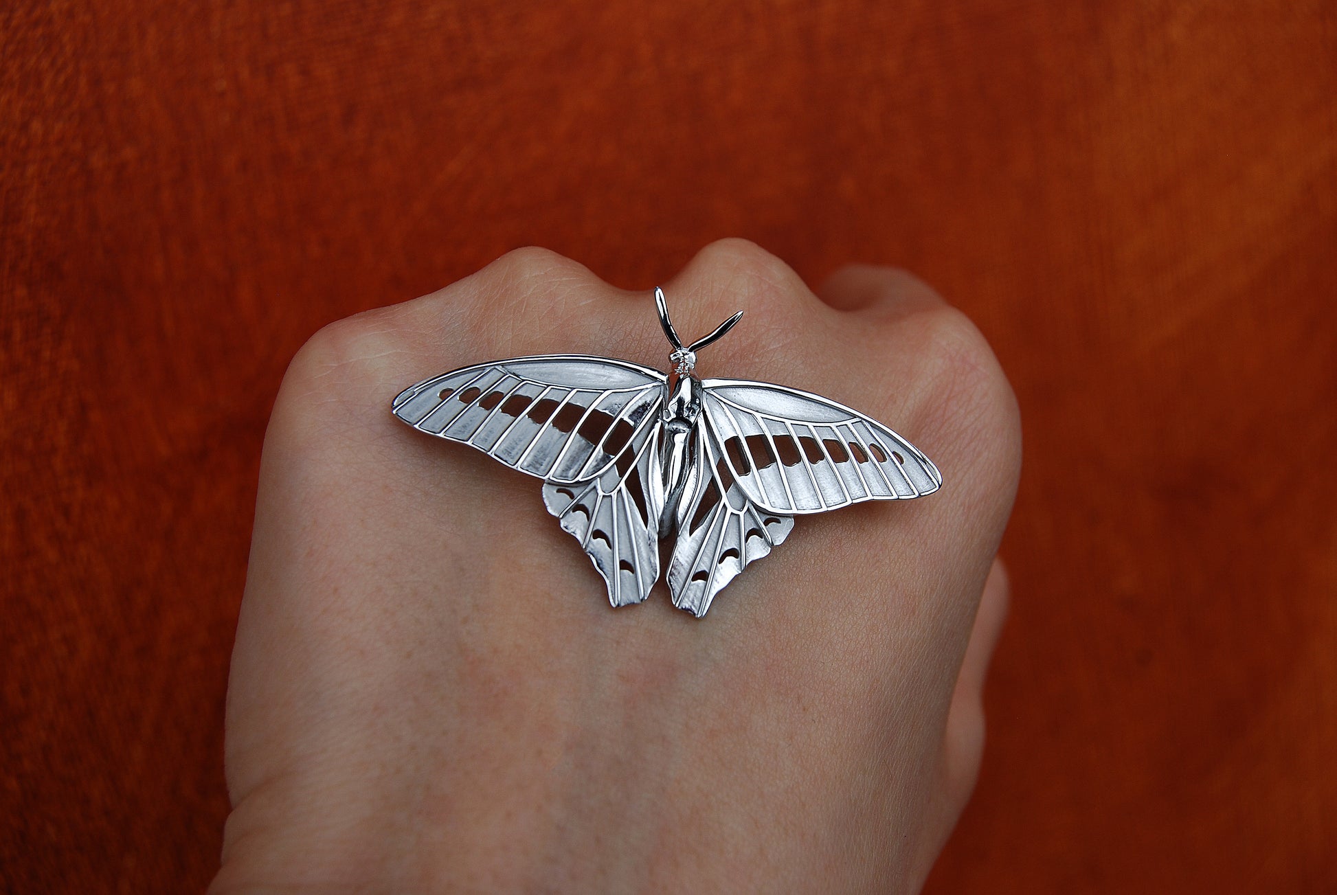 Sterling silver Blue Triangle Butterfly pendant photographed in nature, front view showing vibrant wing contours.
