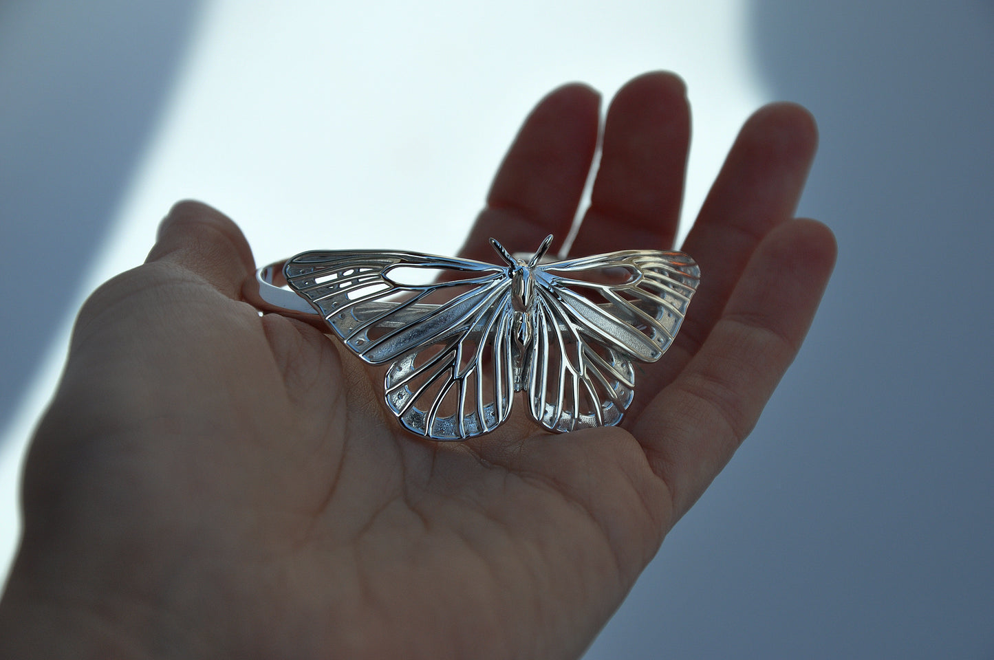 Sterling silver Monarch Butterfly Bracelet held in hand, showcasing handcrafted detail and lightweight cut-out design.