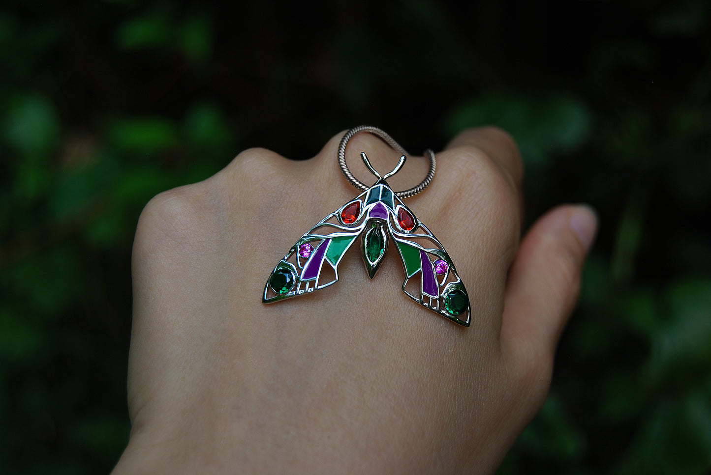 Close-up back view of silver moth pendant necklace on hand 2