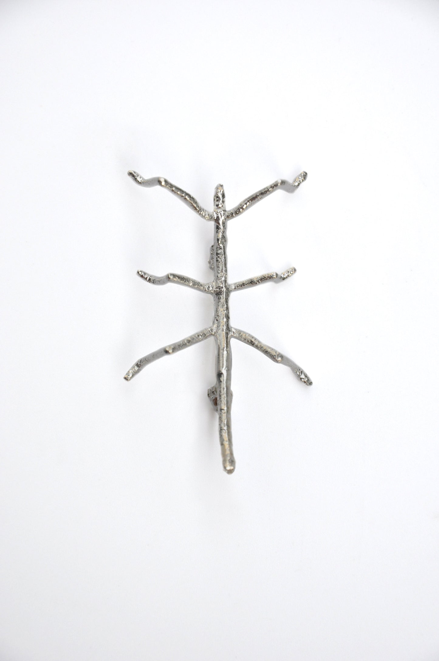 Front view of the silver stick insect brooch on a white background, showing intricate detail and texture.
