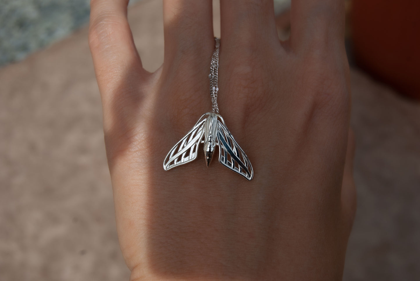 Close-up of a handcrafted sphinx moth pendant