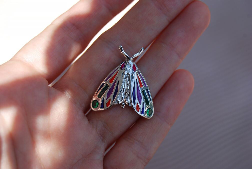 Close-up of hand holding the jeweled Tiger Moth pendant