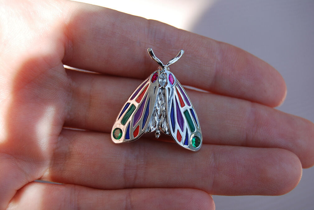 Detailed close-up of Tiger Moth pendant held in hand