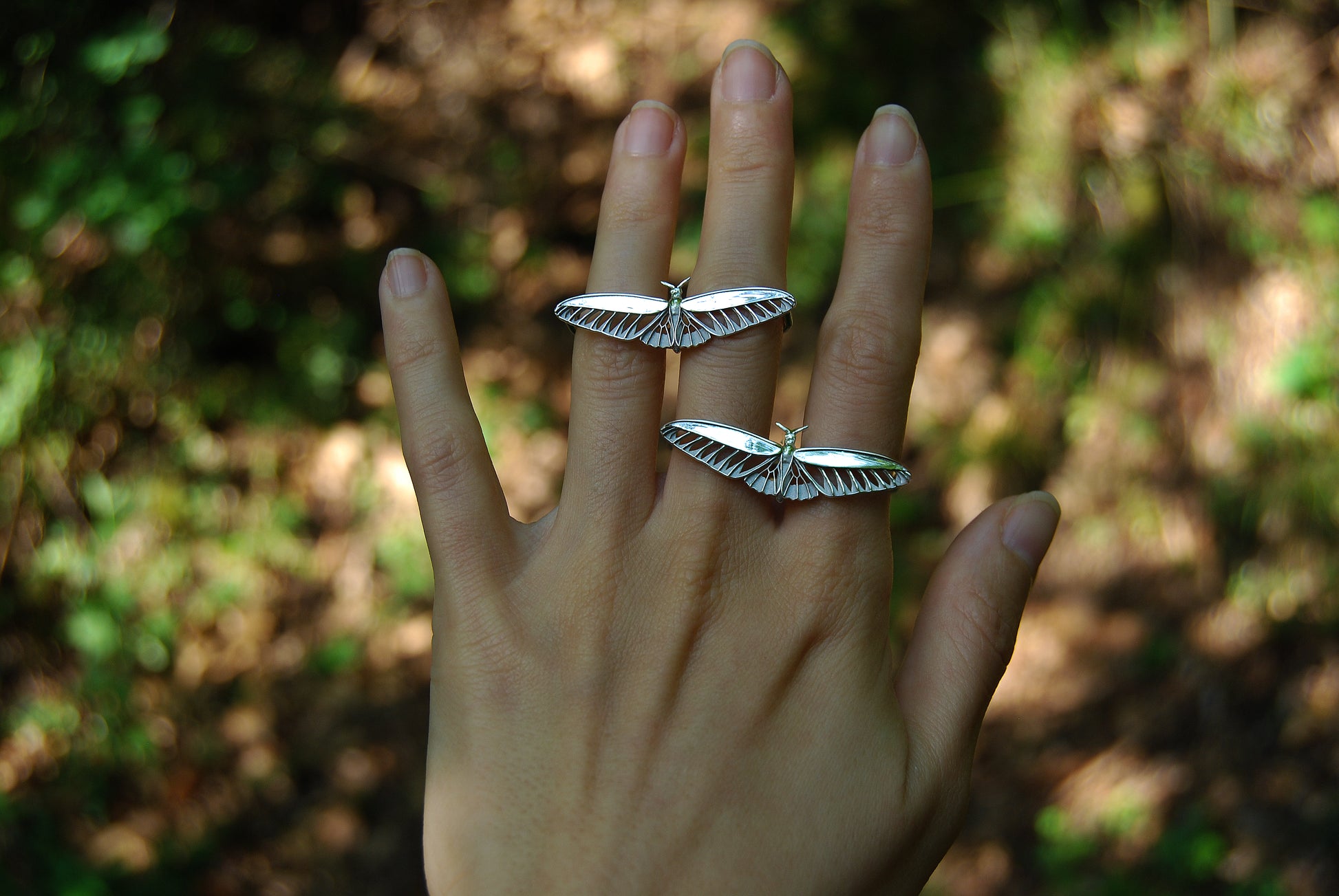 Alternate view of two silver butterfly rings worn together, showcasing layered insect jewelry styling.