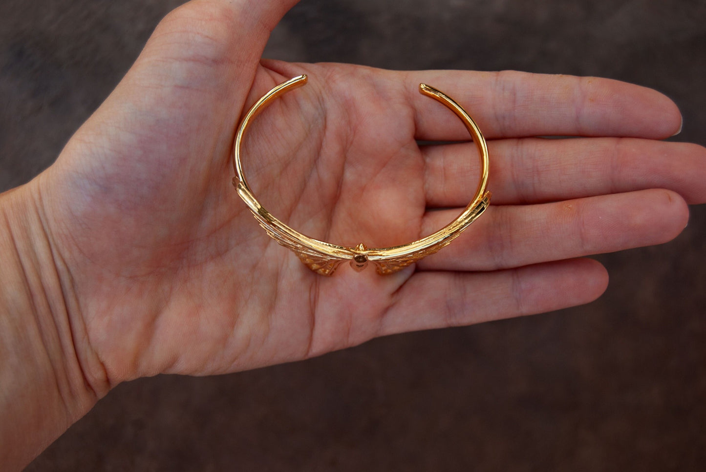 Top view of 14k gold plated Atlas moth bracelet with intricate wing design on white background