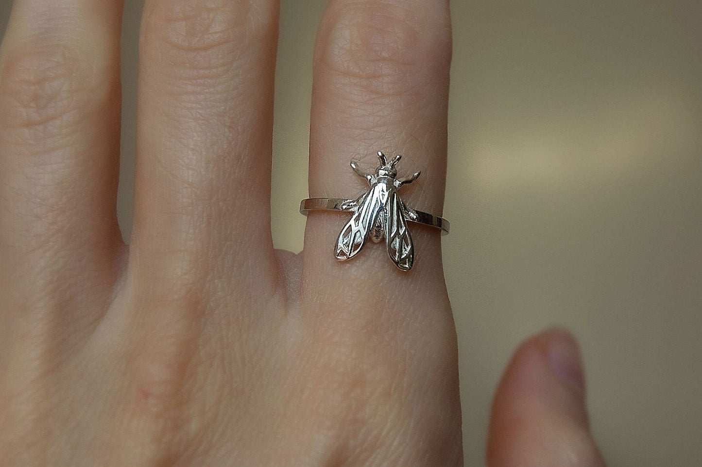 Polished silver wasp-inspired band displayed on a black velvet cushion.