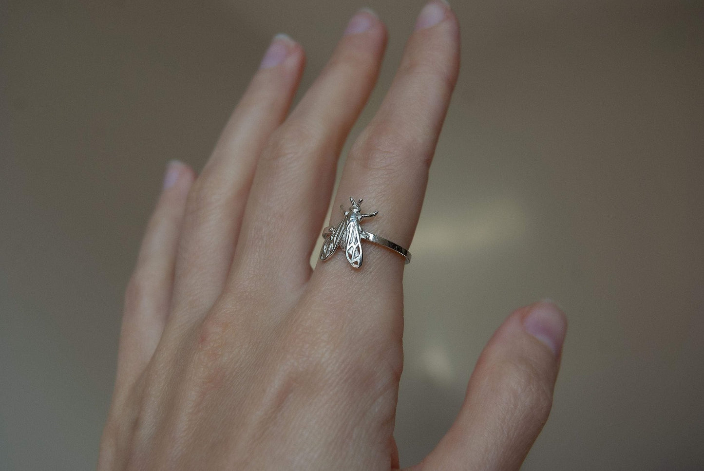 Silver bee ring worn on a finger showing intricate craftsmanship and size.