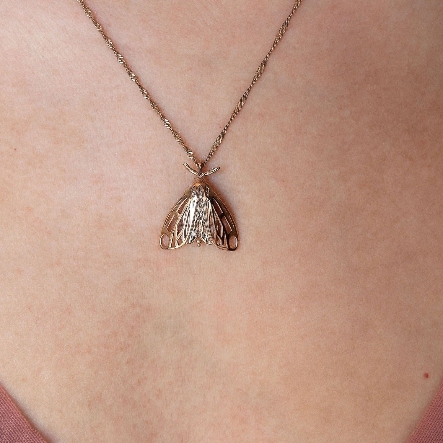 Close-up of model wearing gold artisan moth necklace, focusing on the intricate moth wing detailing.