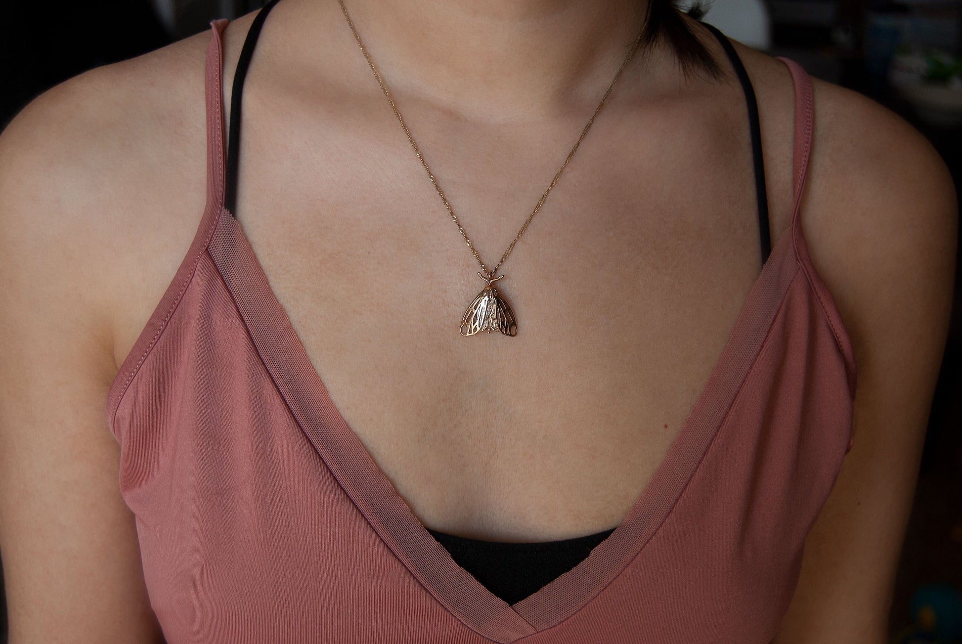 Model wearing gold tiger moth pendant, showcasing a gothic bug pendant with bold, artistic appeal.
