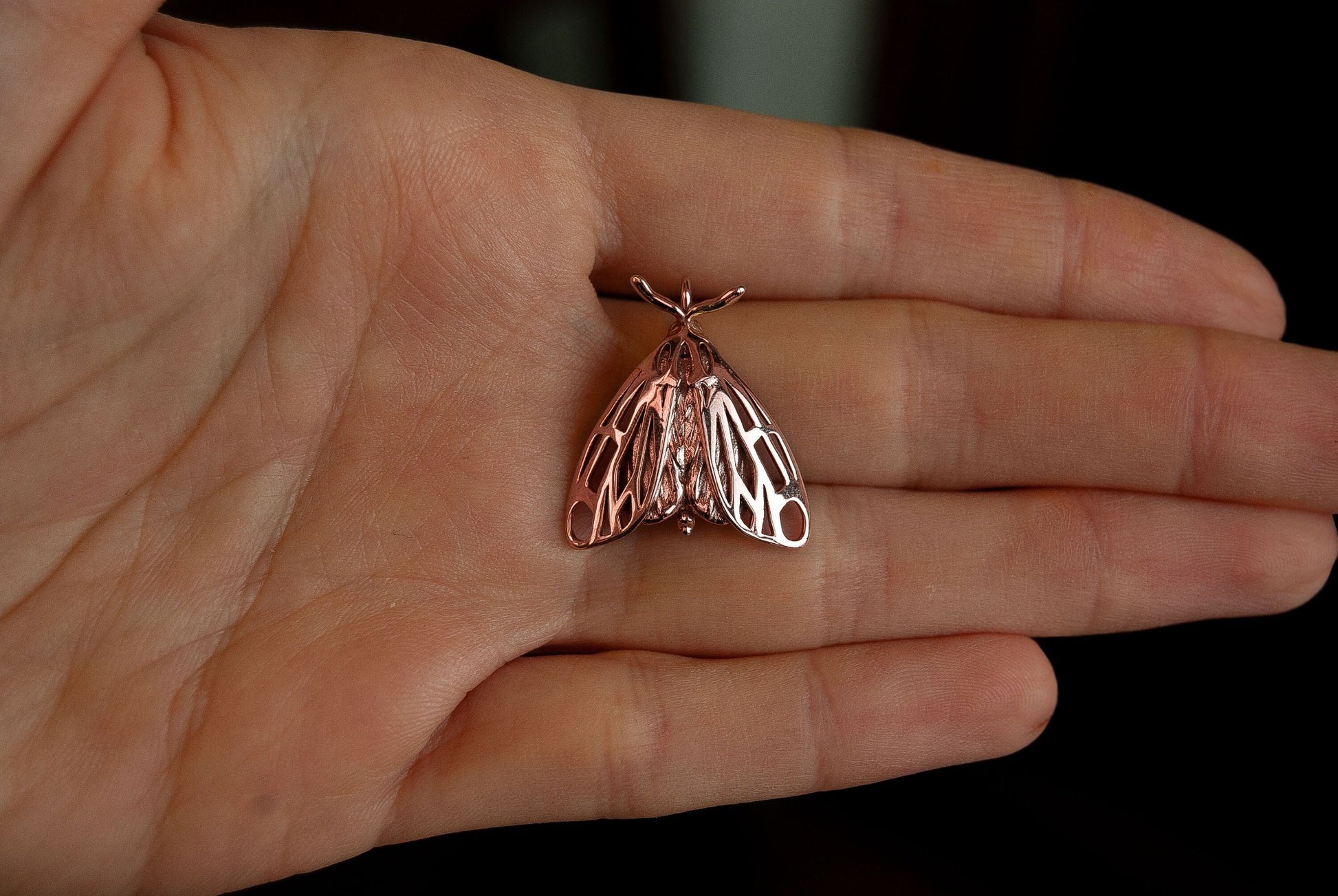 Rose gold handmade insect pendant displayed on hand, combining elegance and natural symbolism.