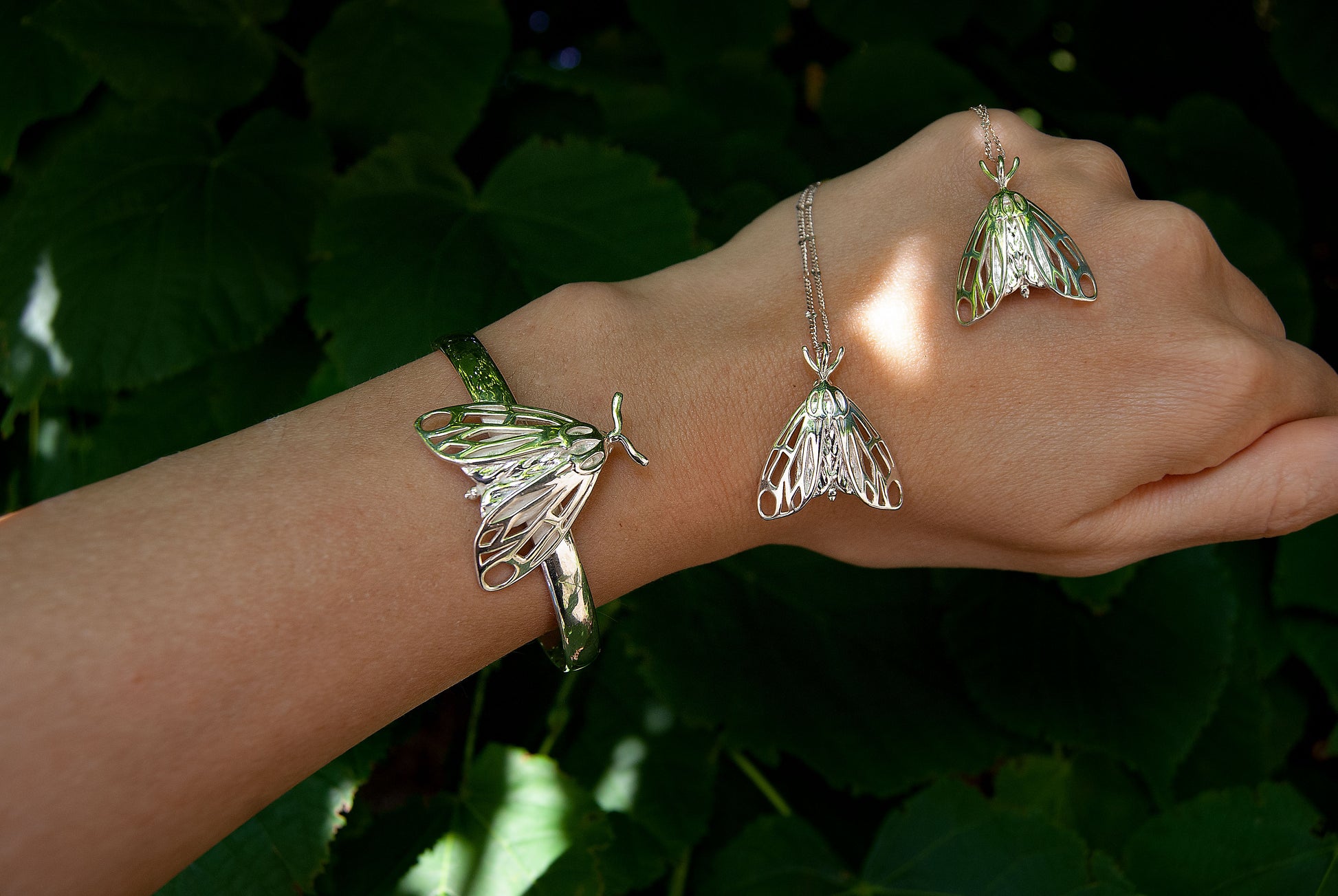 Sterling silver moth charm worn on hand, highlighting the fine craftsmanship of this tiger moth pendant.