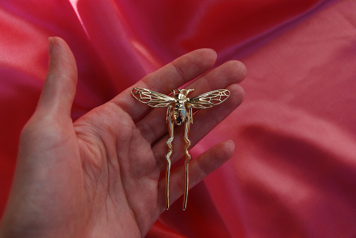 14k gold-plated bee hair pin resting on soft silk fabric, showcasing handcrafted insect-inspired jewelry with elegant metallic shine.