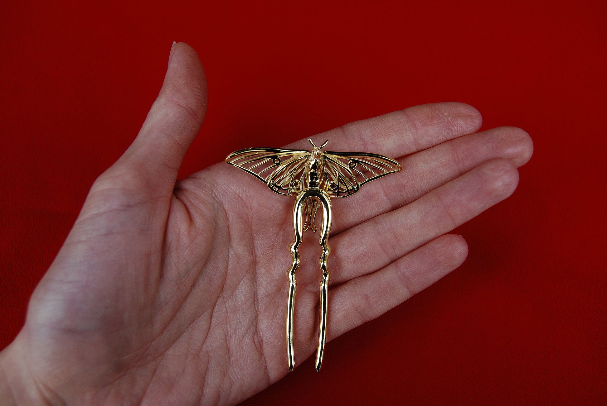 Back view of gold Luna Moth hair pin showing clasp mechanism and structural detailing, highlighting craftsmanship and functional design of insect-inspired jewelry.