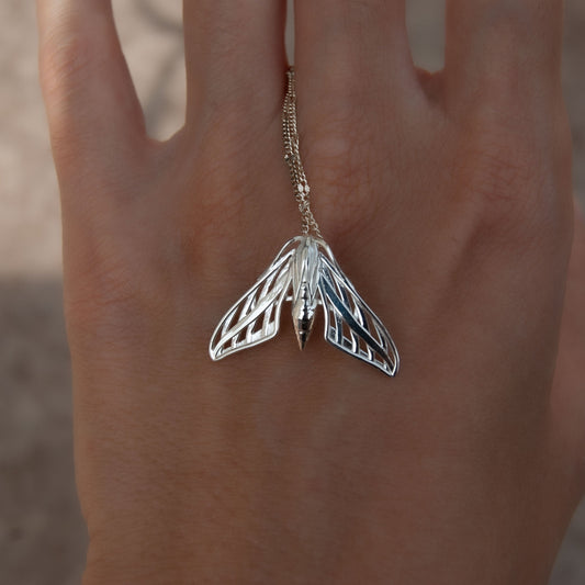 Close-up of a silver handcrafted sphinx moth pendant