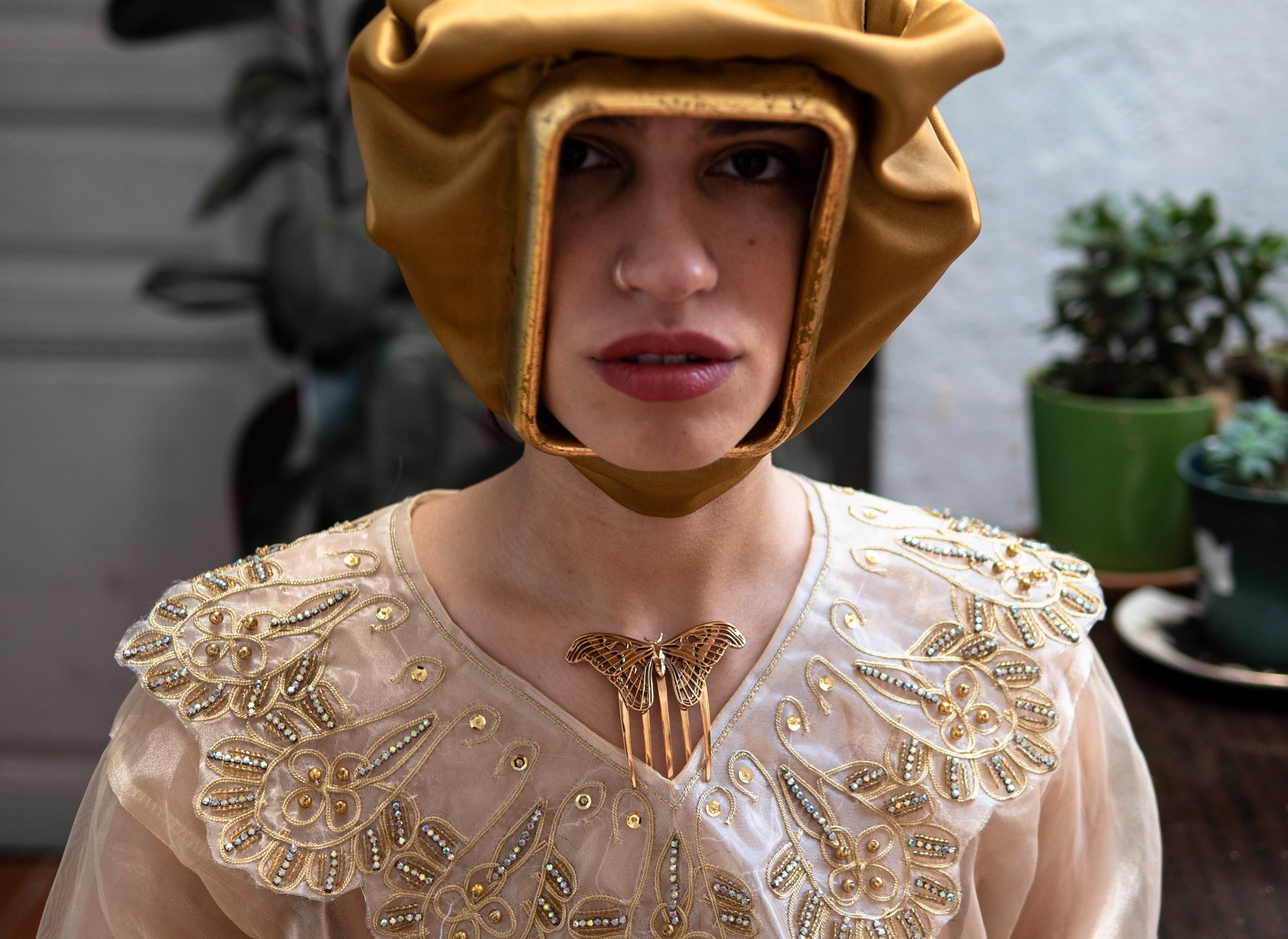 Model wearing a polished bronze Atlas Moth hair comb, styled in an elegant updo; the sculptural insect design adds a dramatic, nature-inspired accent to the look.