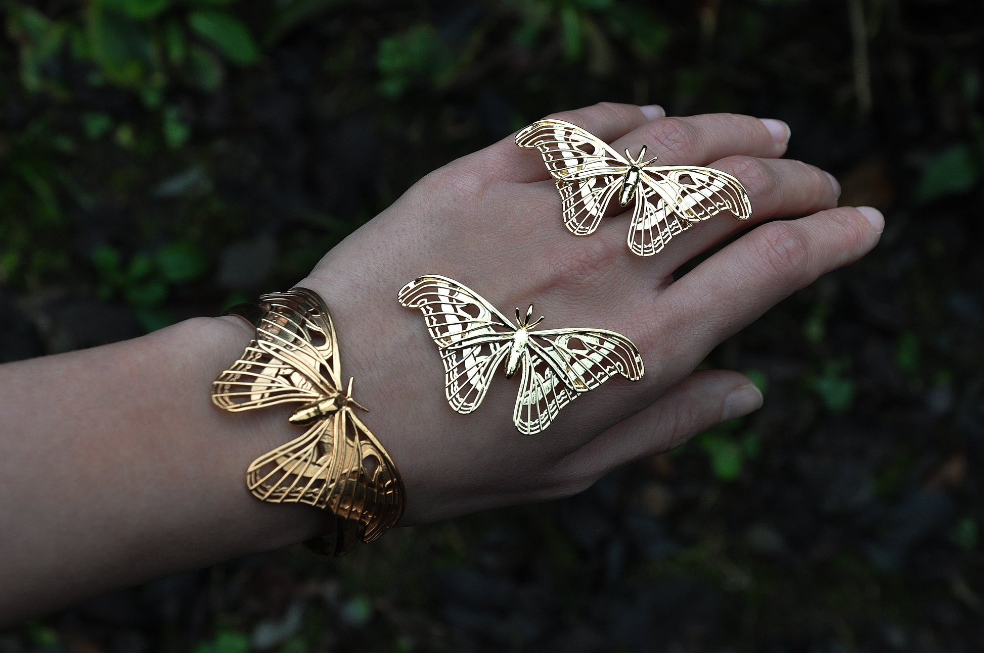 Alternate view of Atlas Moth Pendant and Bracelet in gold, styled on hand with soft natural lighting.