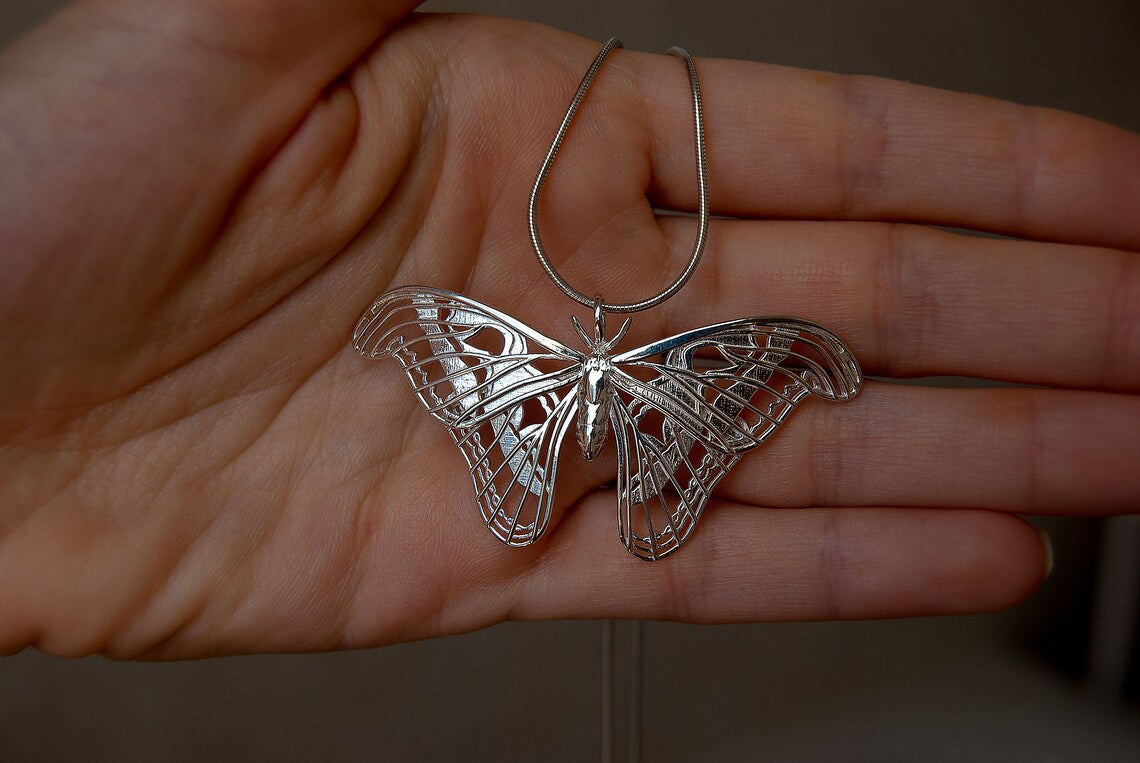 Silver Atlas Moth Pendant held in hand, closeup view of sculptural wings and artisan craftsmanship.