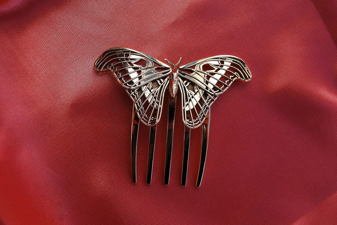 Bronze Atlas Moth sculpture resting on soft silk fabric, highlighting the intricate wing details and warm metallic tones against a luxurious textile backdrop.