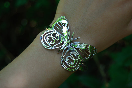 Silver Eighty-eight Butterfly Bracelet worn on hand with green nature background, showcasing organic elegance.