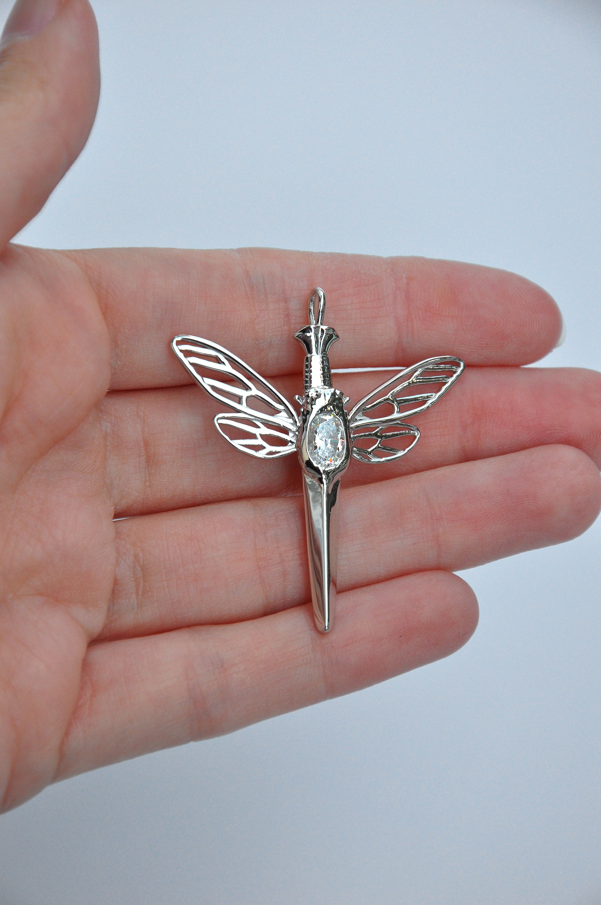 Elegant cicada dagger pendant in silver with white gemstone, representing rebirth and quiet strength
