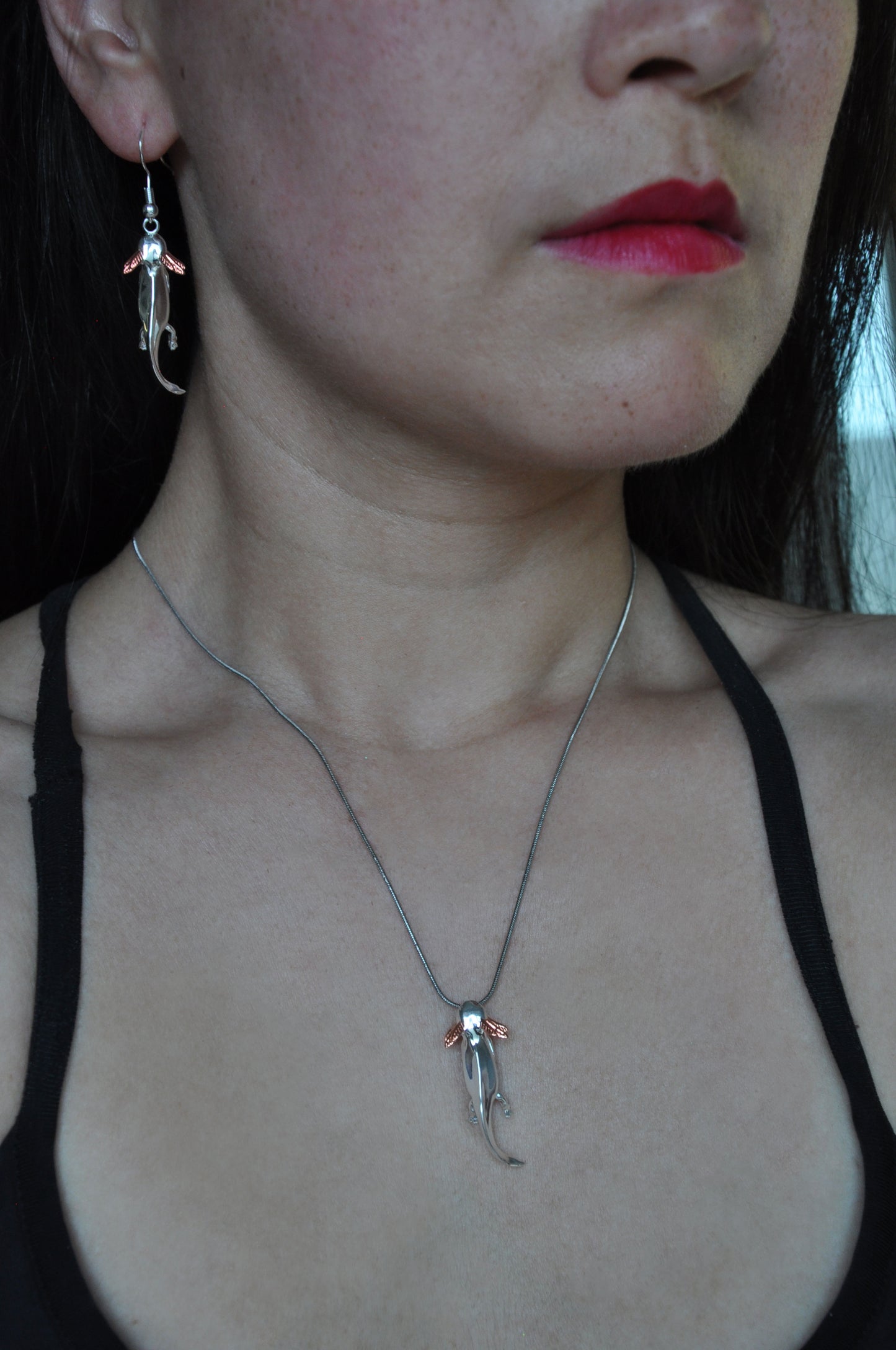 Model wearing the Exolotl pendant and matching earrings, styled with a minimalist outfit to highlight the jewelry’s playful elegance.