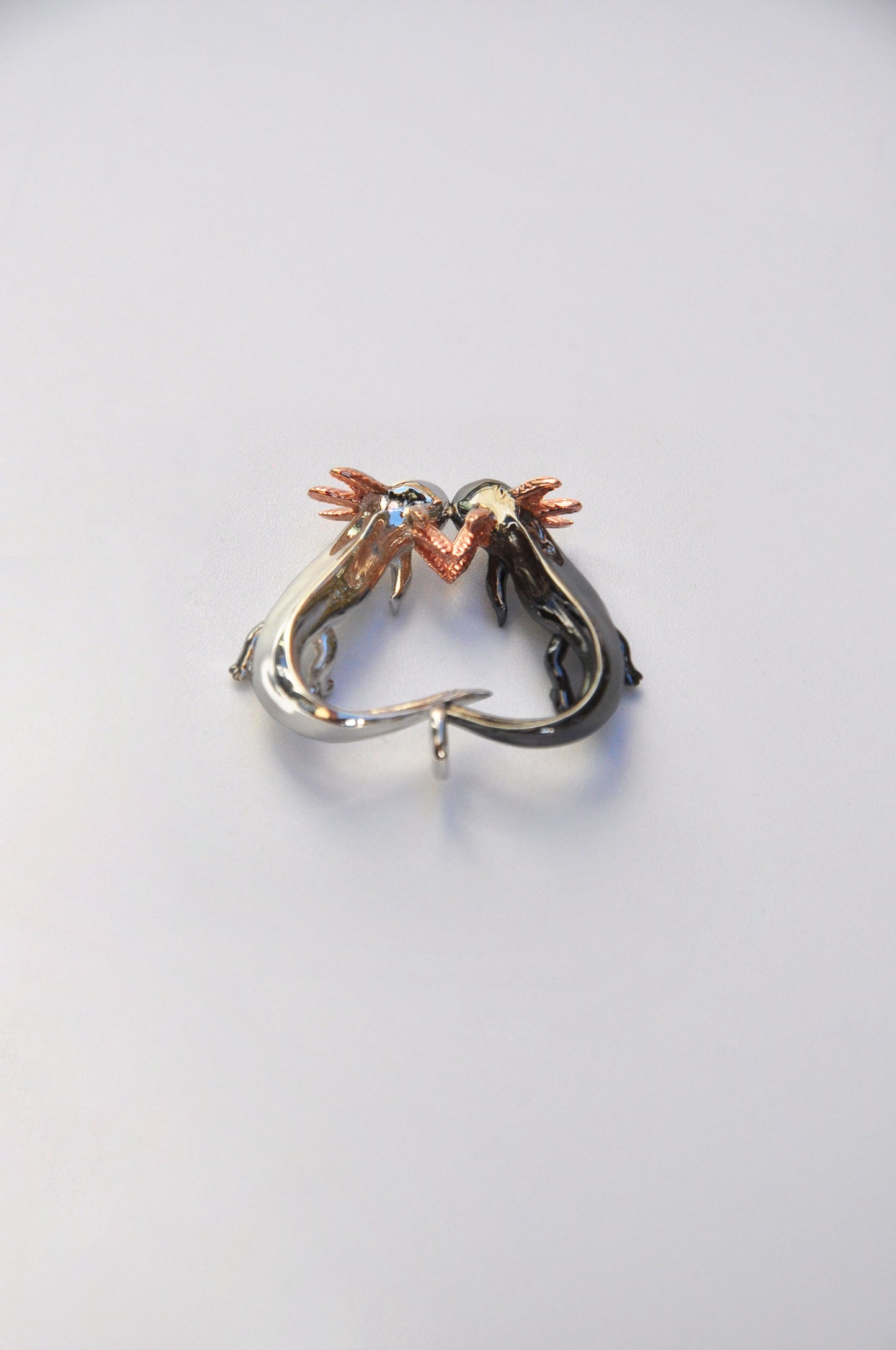 Back view of the Exolotl Love Pendant on a white background, showing smooth contours and subtle detailing.