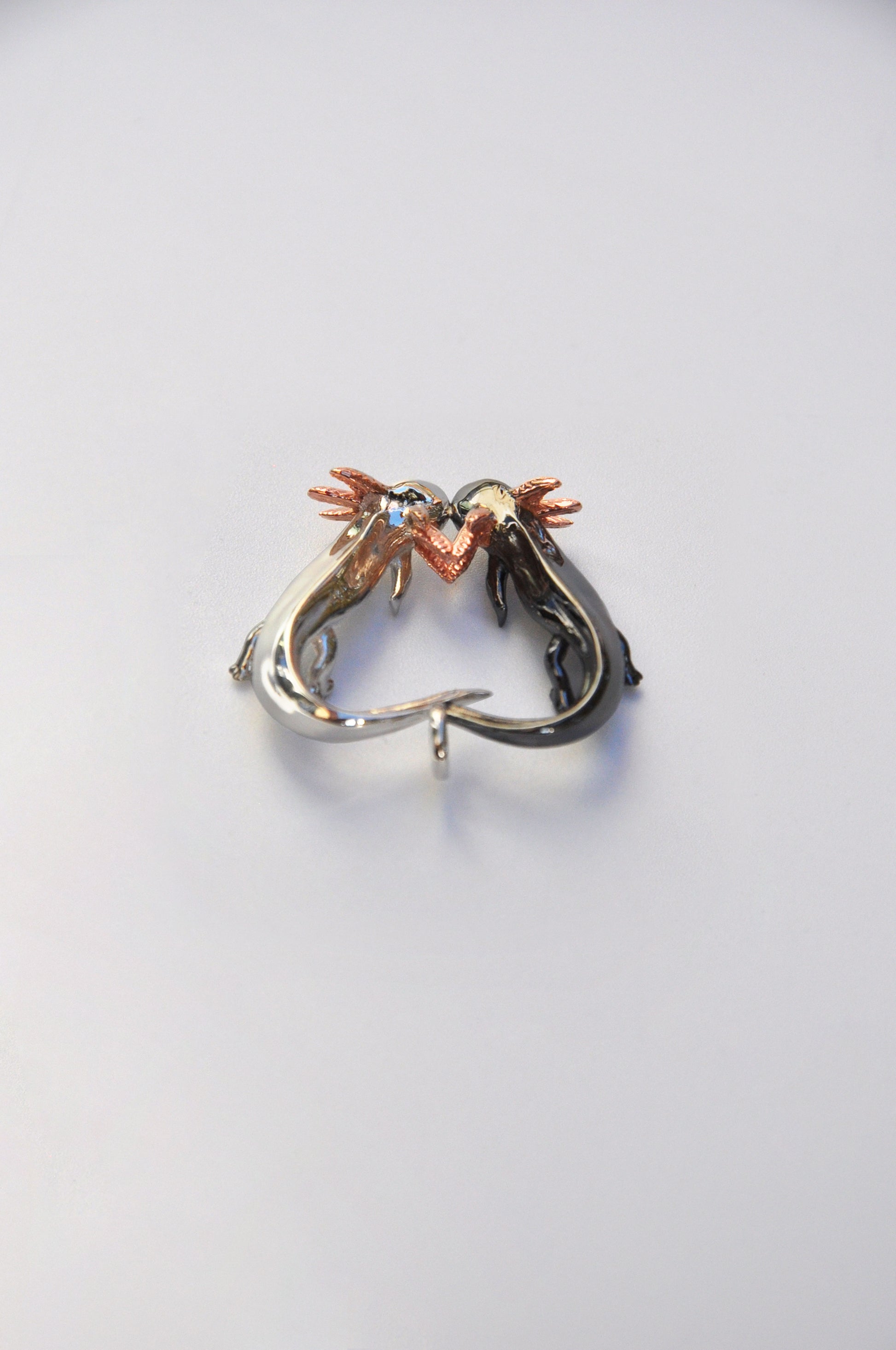 Back view of the Exolotl Love Pendant on a white background, showing smooth contours and subtle detailing.