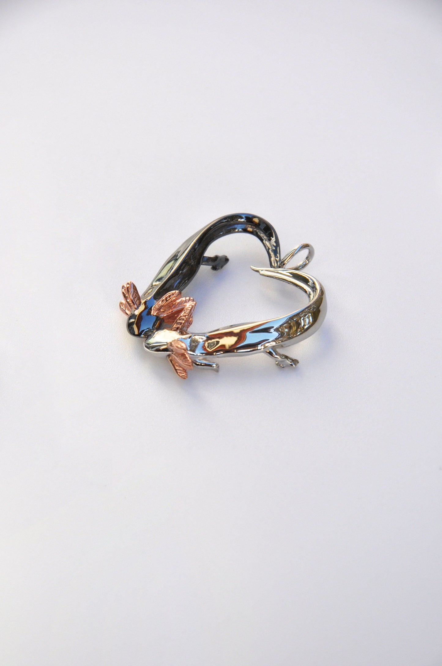 Side profile of the Exolotl Love Pendant on a white background, revealing the layered design and contrast between the two axolotls.