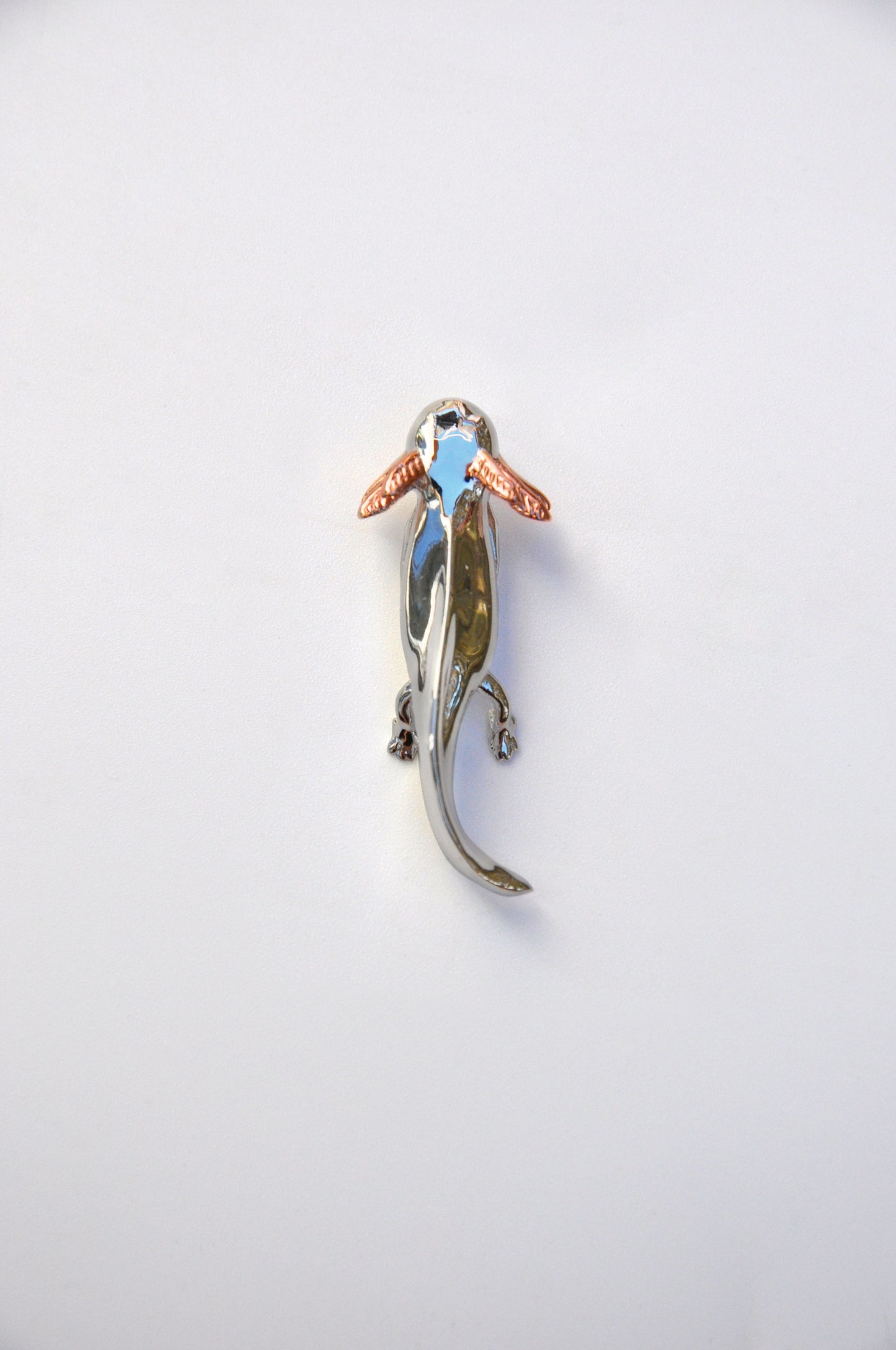 Front view of the handcrafted Exolotl pendant on a white background, showing its sterling silver body and rose gold-plated gills.