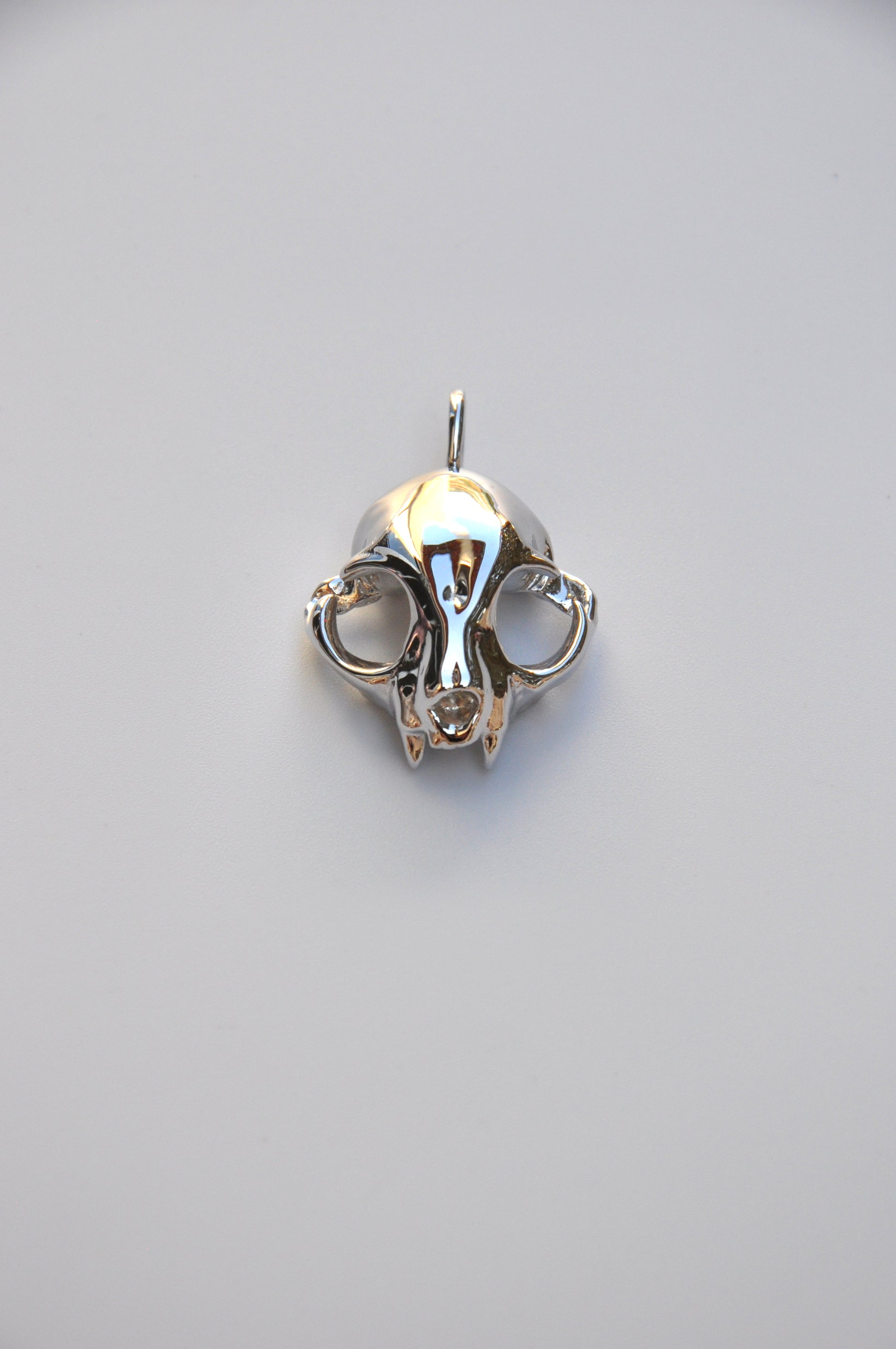 Bottom view of the matching silver feline skull earrings on a white background, highlighting detailed sculpting.