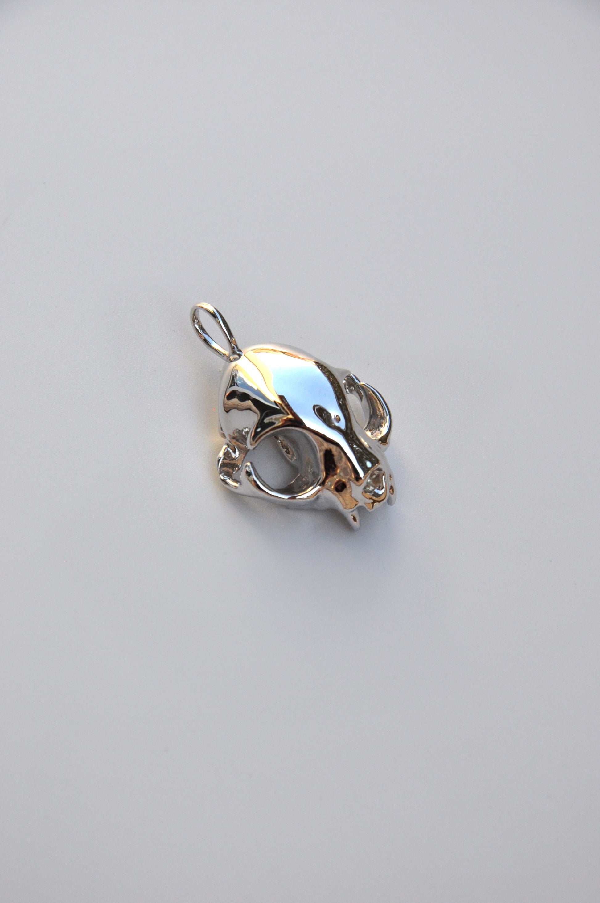 Back view of the silver feline skull earrings on a white background, showing earring clasps and finish.