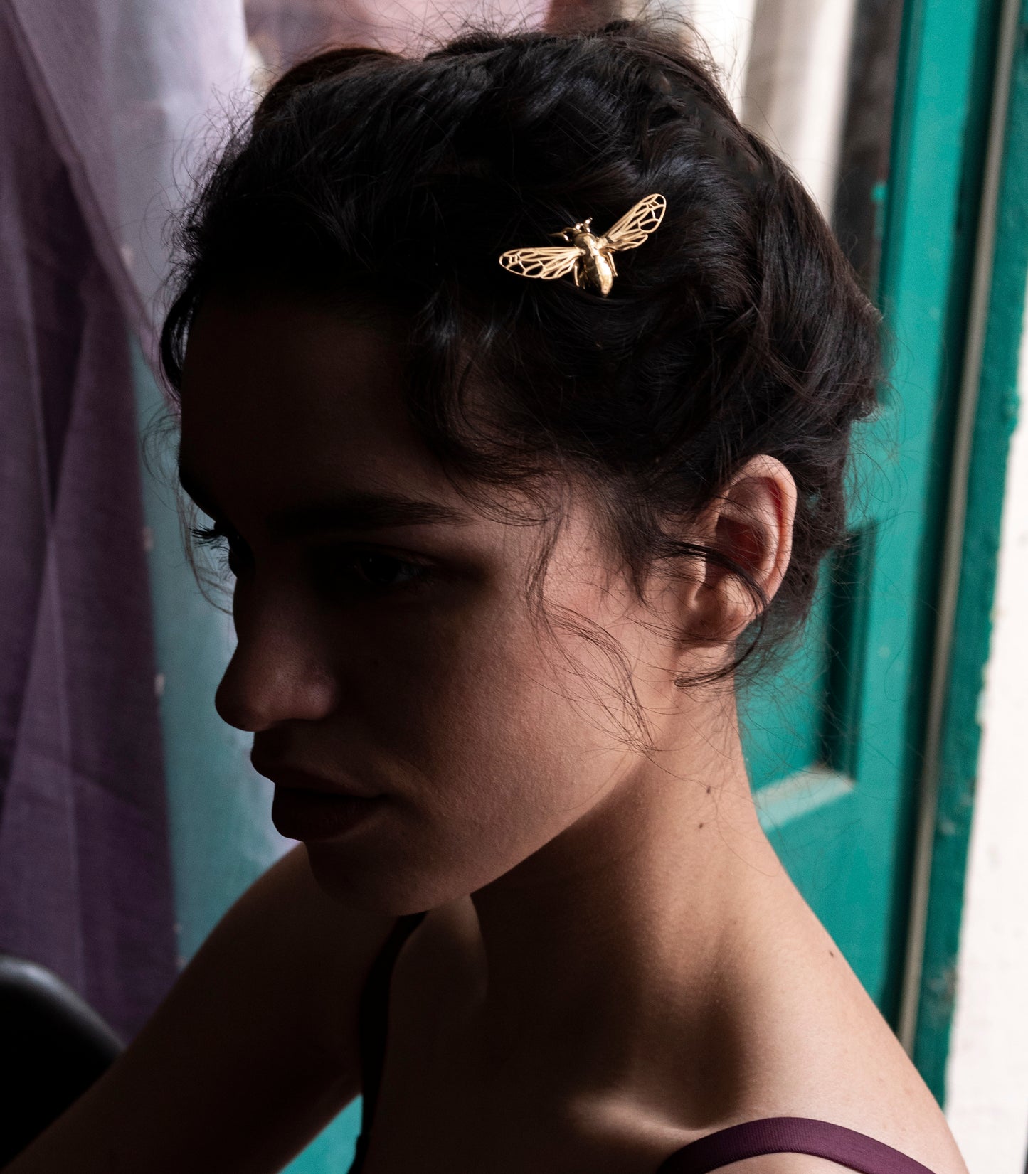 Model wearing a handcrafted gold bee hair pin in an elegant updo, showcasing eco-friendly jewelry with intricate wing details.