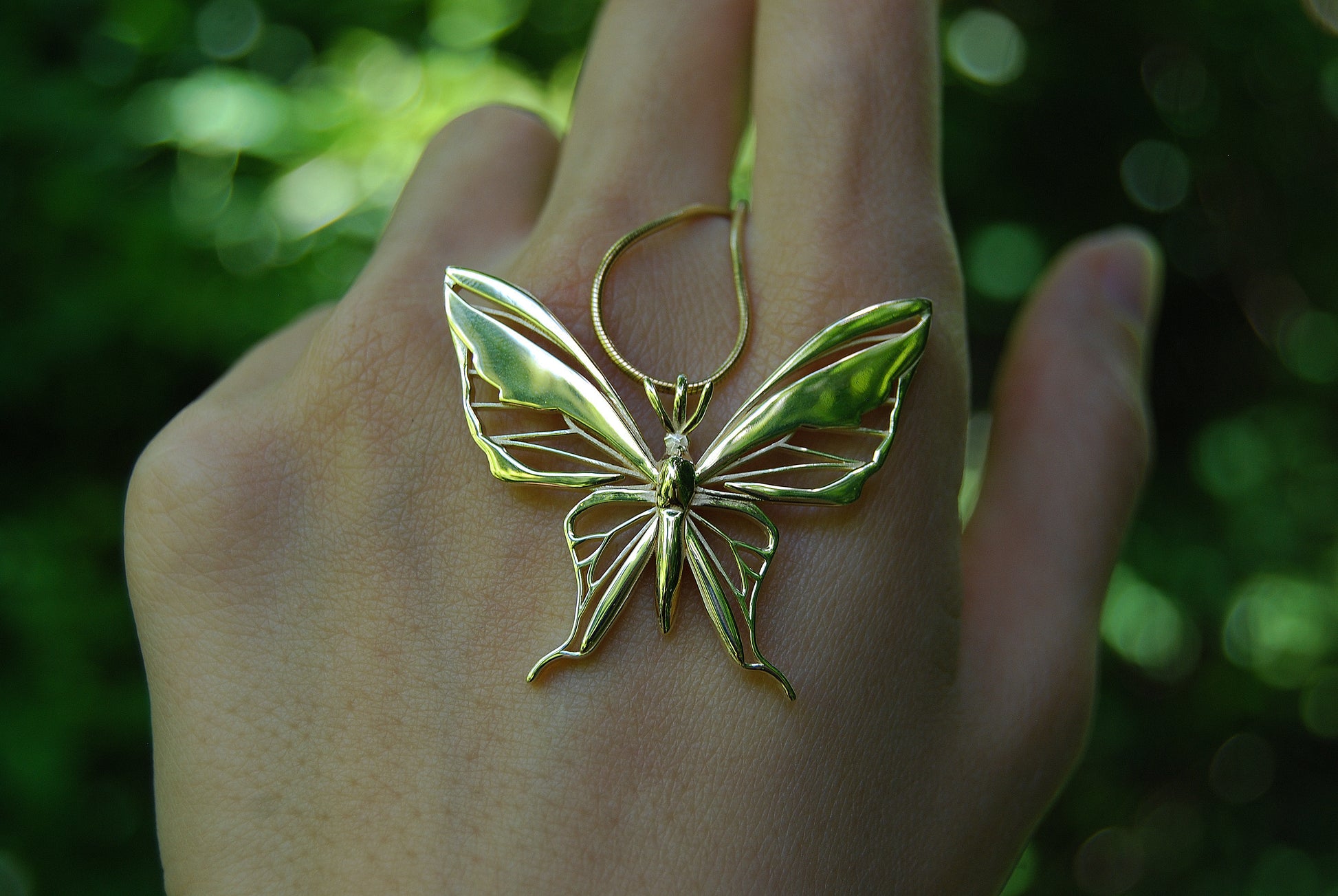 Close-up of gold butterfly pendant necklace on natural background